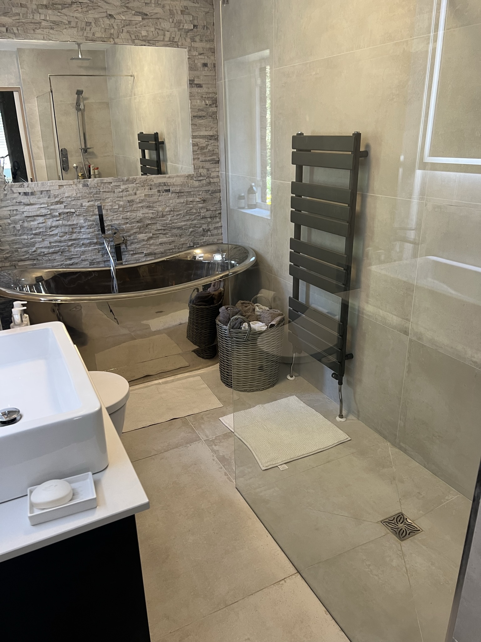 A finished bathroom with a freestanding bath, stone feature wall and walk-in shower, fitted by Britannia Building Co in Liverpool