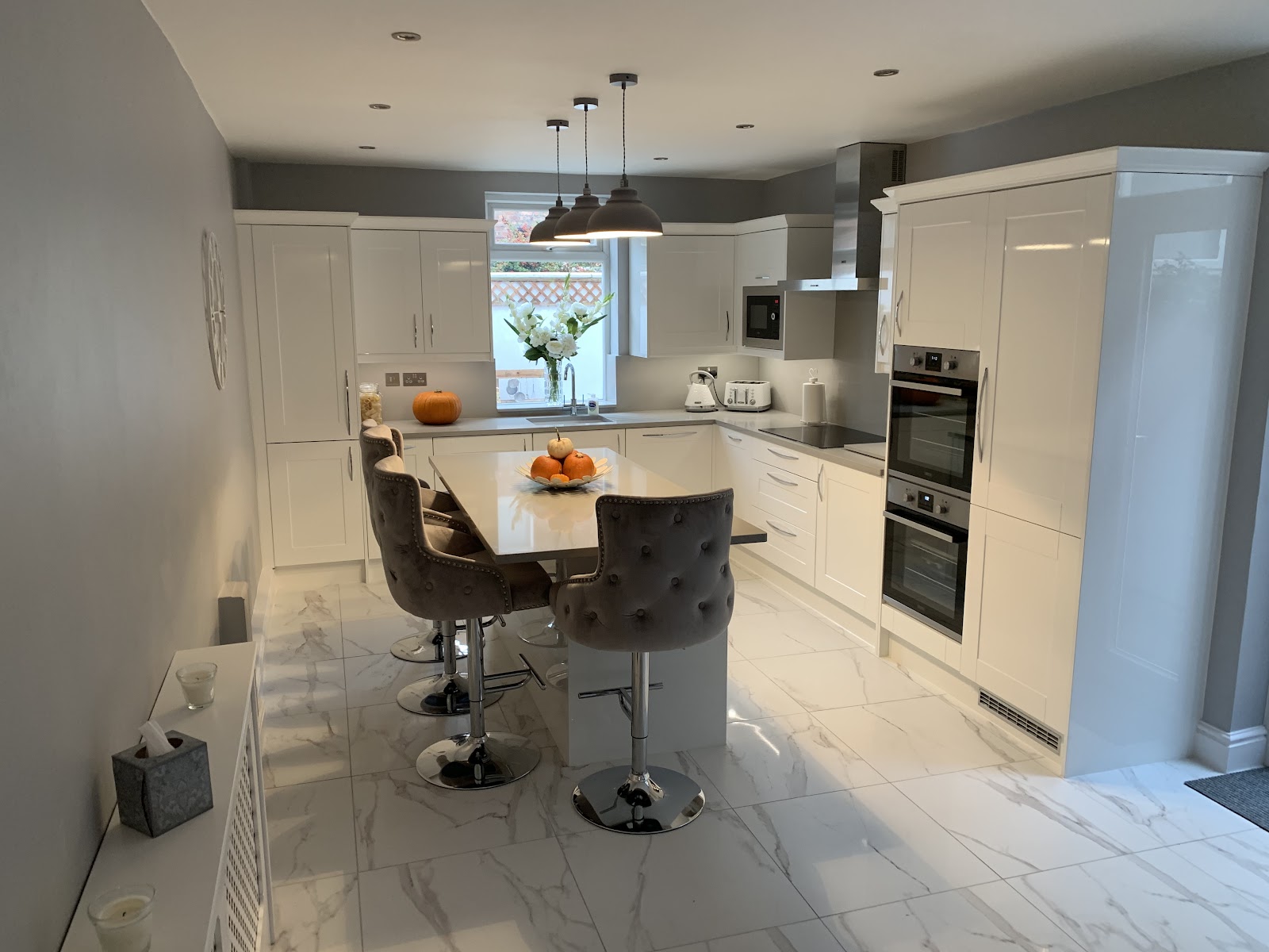 Bright white shaker kitchen with marble-effect flooring and an island